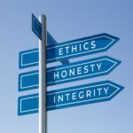 A signpost against a blue sky pointing toward ethics, honesty, and integrity